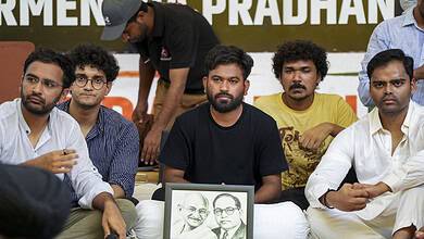 Protesters seated with framed photo of Mahatma Gandhi and Dr. B.R. Ambedkar at a rally in Delhi.