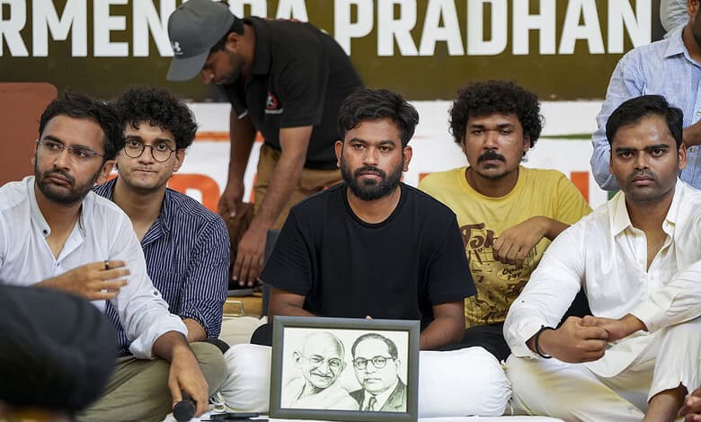 Protesters seated with framed photo of Mahatma Gandhi and Dr. B.R. Ambedkar at a rally in Delhi.