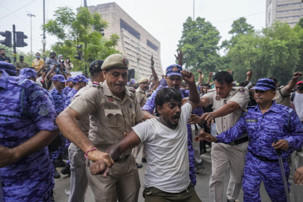 Police detain a protester during a demonstration in an urban area.