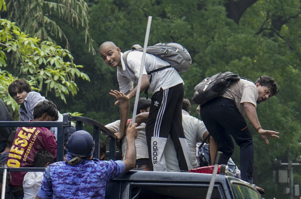 Group of young men traveling on a truck in a green outdoor setting.