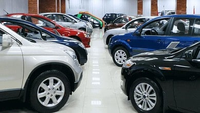 Variety of new cars displayed in a spacious indoor showroom for sale.