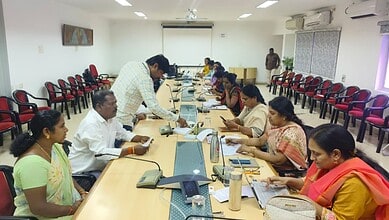 Officials and citizens at a grievance redressal meeting in a conference room.