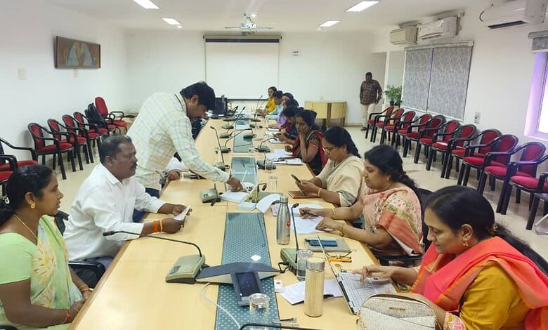 Officials and citizens at a grievance redressal meeting in a conference room.