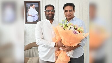 Two Indian politicians holding a large bouquet of flowers during a formal event.