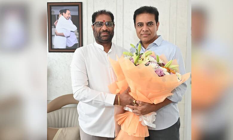 Two Indian politicians holding a large bouquet of flowers during a formal event.
