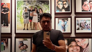 Ram Kapoor taking a selfie in front of a wall of family photos at an exhibition.