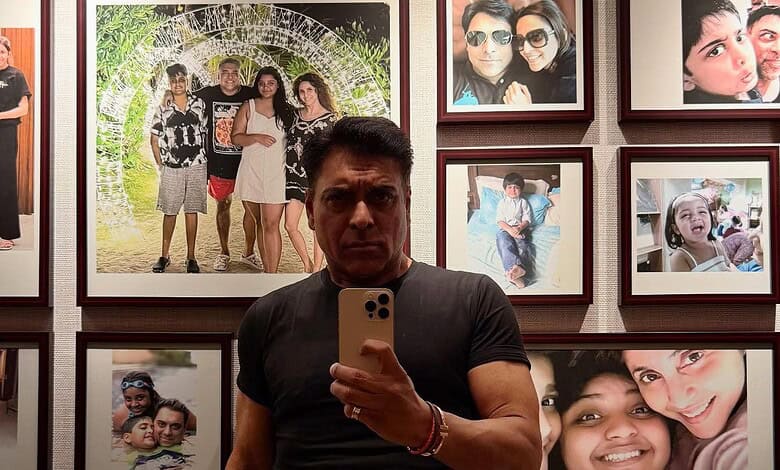Ram Kapoor taking a selfie in front of a wall of family photos at an exhibition.