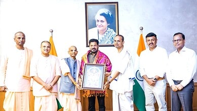 Group of men and women standing with Indian flags and a framed certificate in a formal setting.
