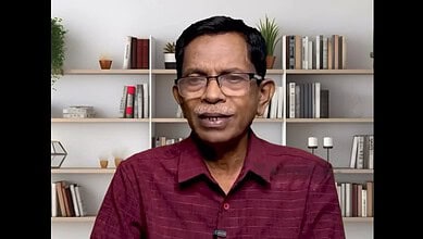 Right-wing commentator wearing glasses and a maroon shirt in a home office setting.