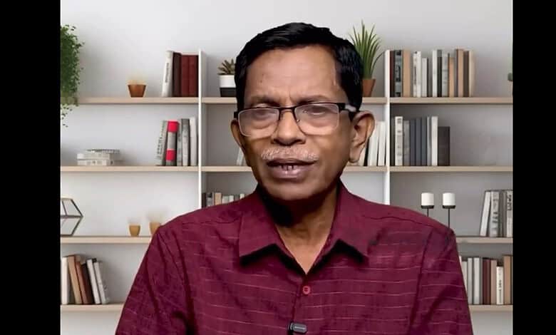 Right-wing commentator wearing glasses and a maroon shirt in a home office setting.