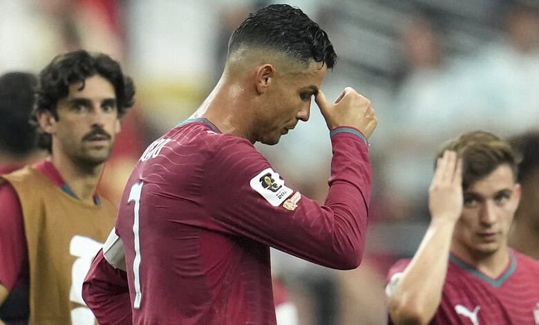 Cristiano Ronaldo in Portugal jersey, looking down with hand on forehead, during FIFA World Cup game.