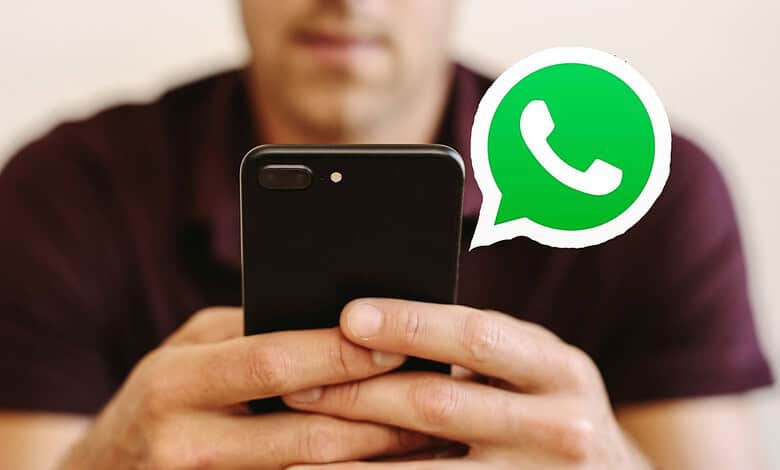 Person holding smartphone with WhatsApp logo visible, engaging in messaging.