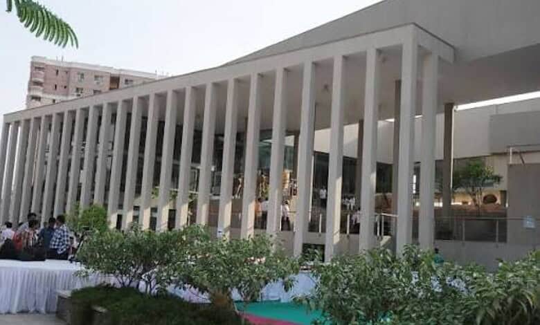 Modern building with vertical white columns and outdoor seating area with people.