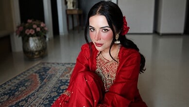 Sara Gurpal in a red traditional outfit with makeup and a flower in her hair.