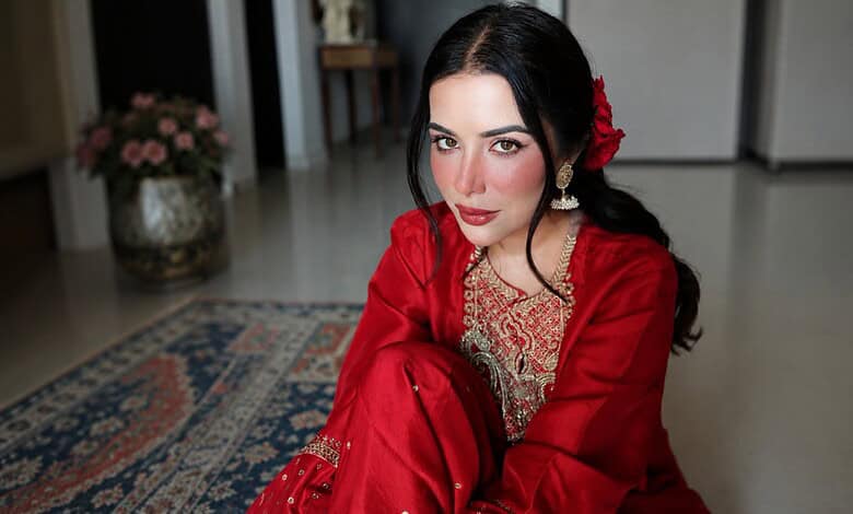 Sara Gurpal in a red traditional outfit with makeup and a flower in her hair.