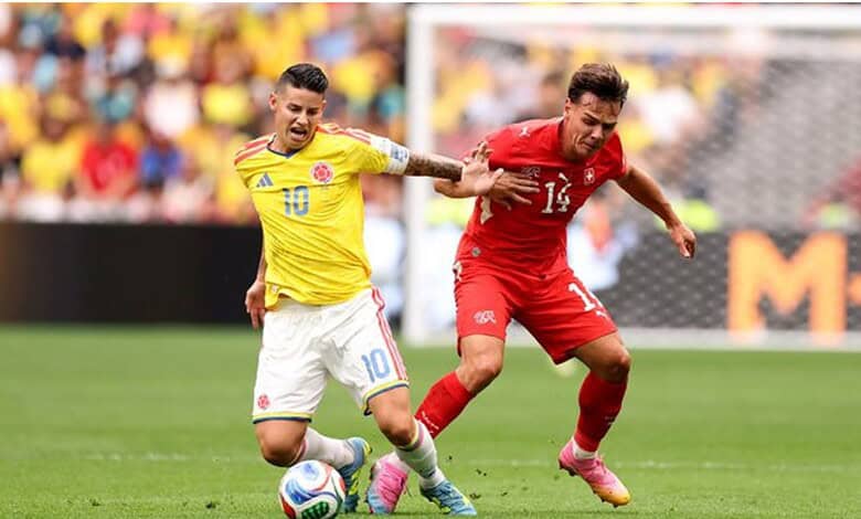 Two soccer players competing for the ball during a match, one in yellow and the other in red.