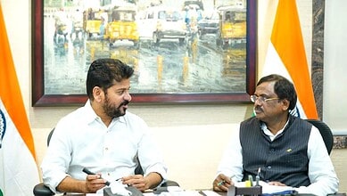 Two men in a formal meeting, discussing in an office with a painting and Indian flags in the background.