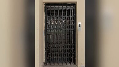 Closed elevator door with safety gate in a building corridor.