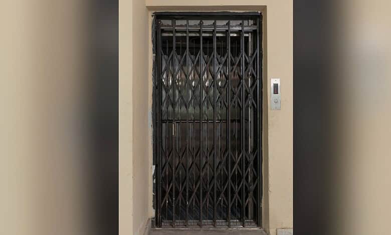 Closed elevator door with safety gate in a building corridor.