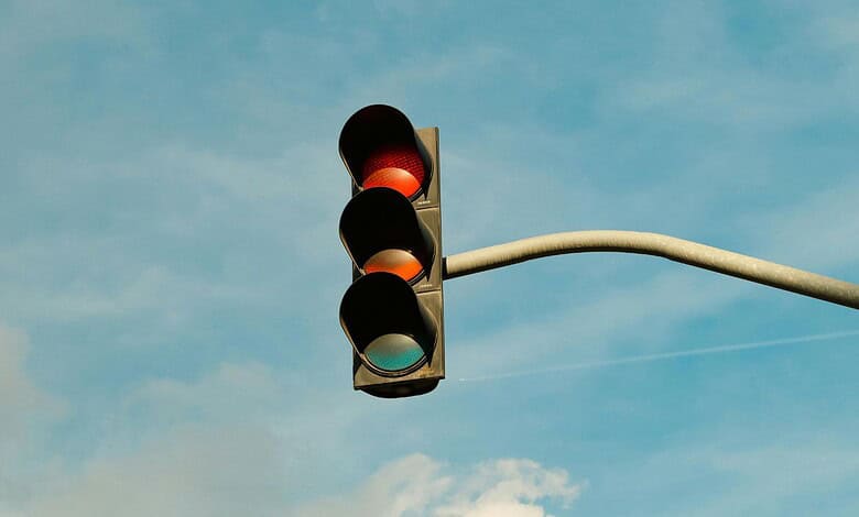Traffic light showing red signal against a blue sky with clouds.