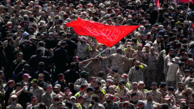 Uniformed members of the Islamic Revolutionary Guard Corps wave a Shiite religious flag during the funeral procession of the slain Iranian Supreme Leader Ayatollah Ali Khamenei and members of his