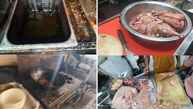 Dirty kitchen with oil spills and raw chicken on a red cutting board in Hyderabad restaurant.