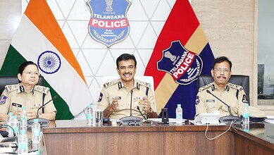 Telangana Police officials at a press conference with Indian and Telangana flags in the background.