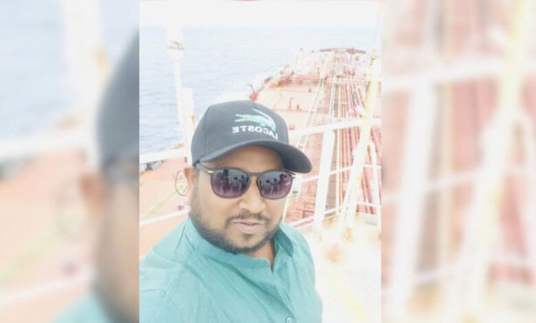 Seafarer wearing sunglasses and cap on a ship deck with ocean background.