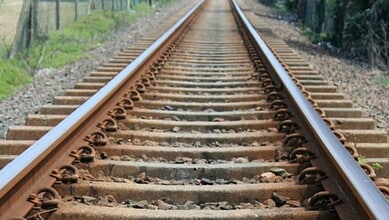 Empty railway tracks extending into the distance in a rural setting.