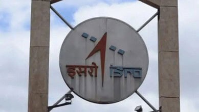 ISRO logo on a large circular signboard against a cloudy sky background.