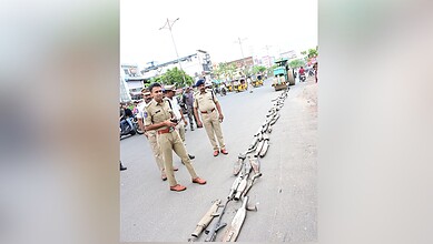Police officers display a line of confiscated silencers on the road in Adilabad.