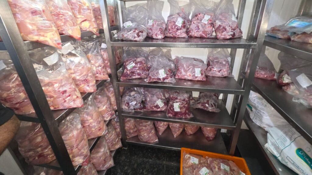 Meat packages stored on metal shelves in a food storage room during KFC Pista House food raids.