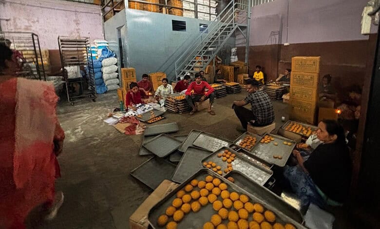 Workers packaging oranges in a warehouse with boxes and trays for distribution.