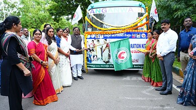 Telangana officials and women gather around an Anganwadi bus during a community event.
