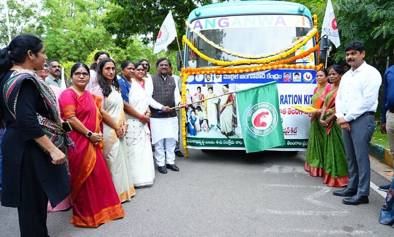 Telangana officials and women gather around an Anganwadi bus during a community event.