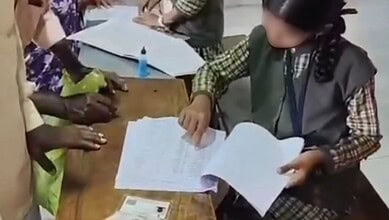 School student reviewing documents during voter list revision in Belagavi village.
