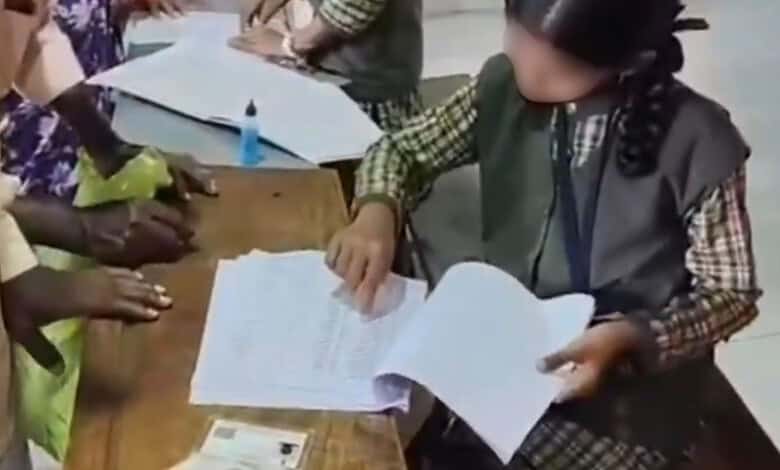 School student reviewing documents during voter list revision in Belagavi village.