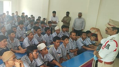 School children listening attentively to a traffic police officer in a classroom setting.