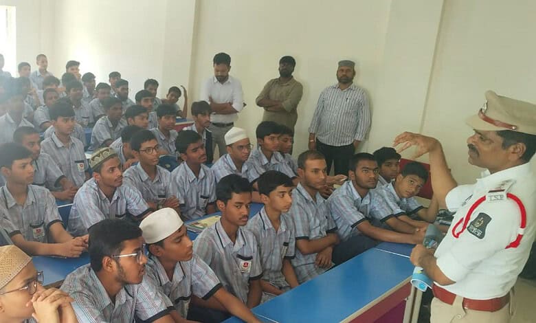 School children listening attentively to a traffic police officer in a classroom setting.
