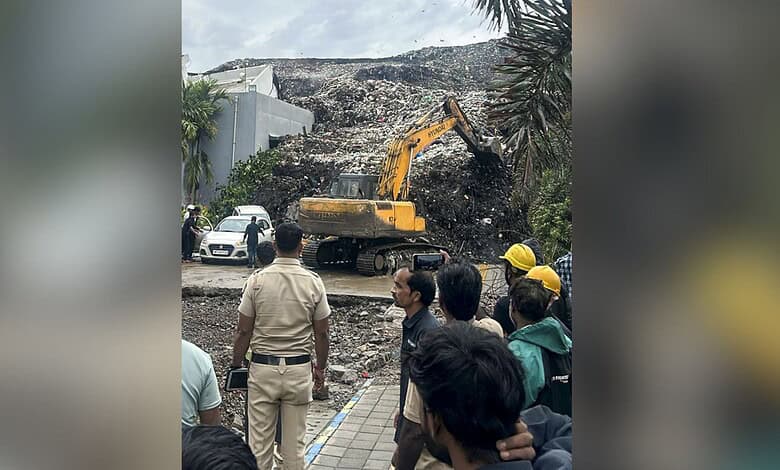 Excavator removing debris from collapsed building caused by garbage mound in Pune.