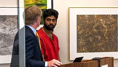 Indian man in red shirt at a court hearing with a lawyer in a suit.