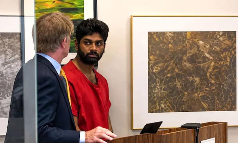 Indian man in red shirt at a court hearing with a lawyer in a suit.