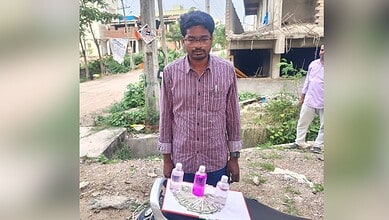 Young man selling colourful bottles on a street in an urban area.