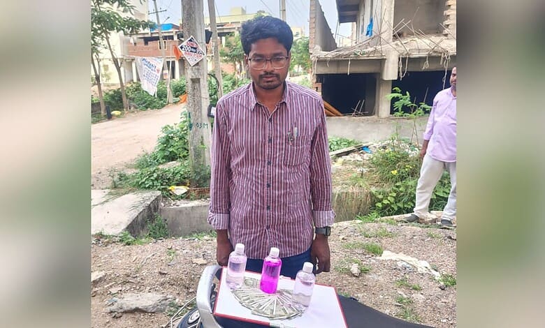Young man selling colourful bottles on a street in an urban area.