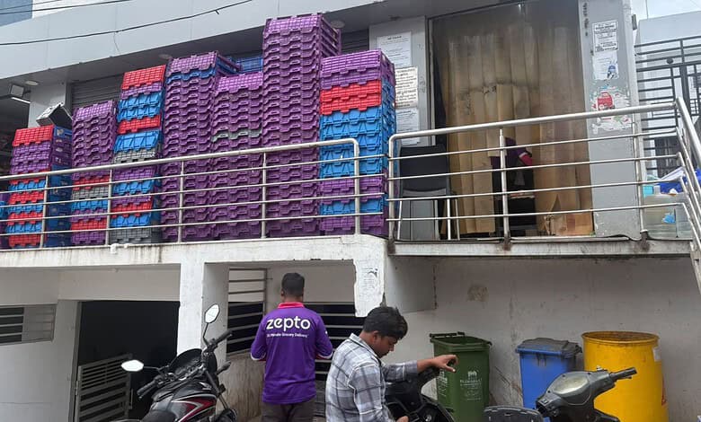 Zepto delivery staff at Narsingi facility during inspection, with stacked crates and waste bins nearby.
