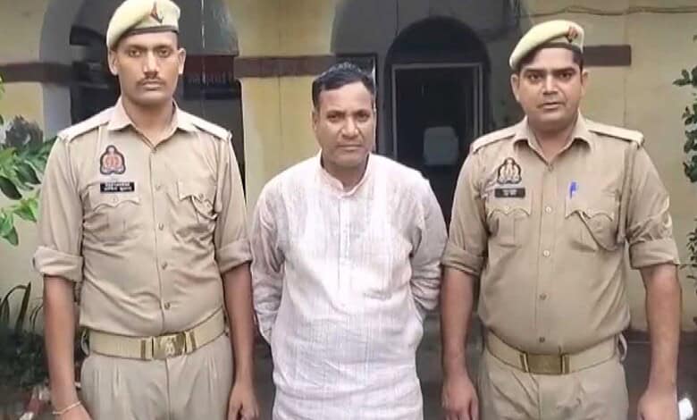Man in white kurta detained by two police officers outside a building in Uttar Pradesh.