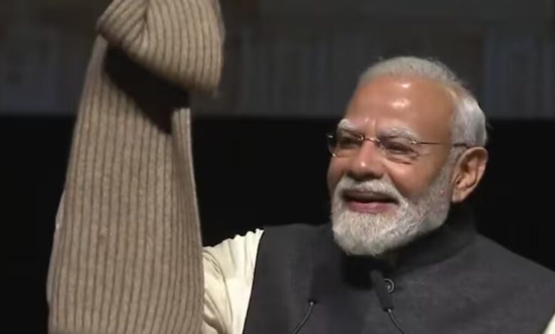 Indian Prime Minister Narendra Modi smiling and waving at a public event.