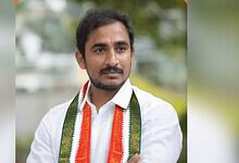 Man with a white shirt and tricolour scarf at a political event.