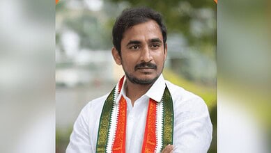 Man with a white shirt and tricolour scarf at a political event.