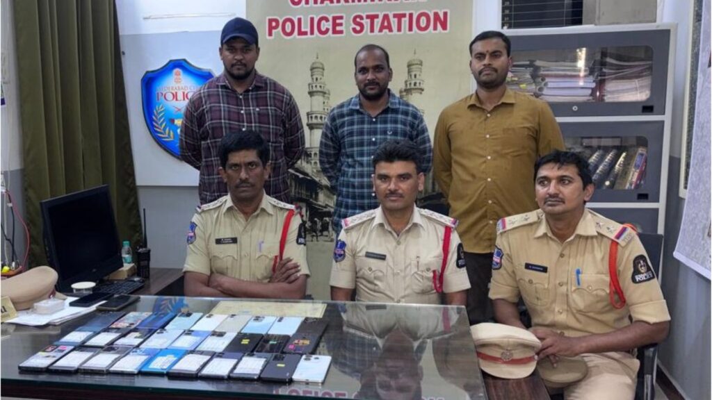 Police officers and staff in police station with mobile phones displayed on table.